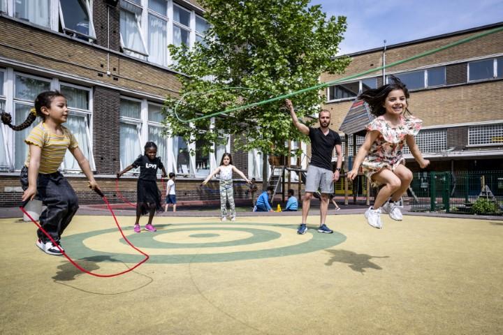 Kinderen touwtjespringen op de speelplaats van basisschool Optimist.